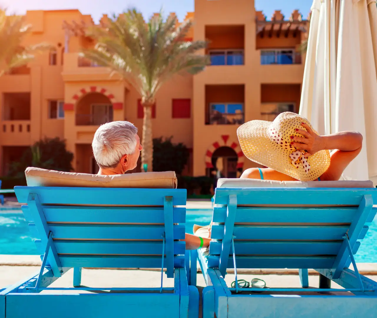 Elderly couple relaxing by hotel pool.