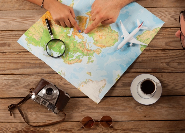 Hands pointing at map with travel items.