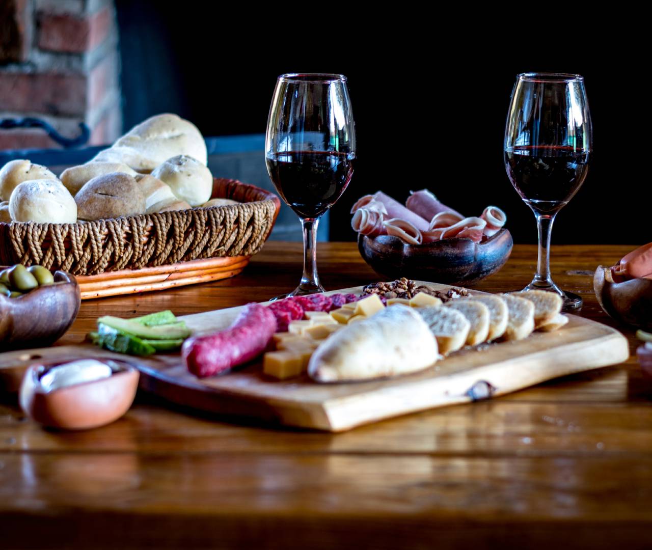 Wine, charcuterie board, and bread on table.