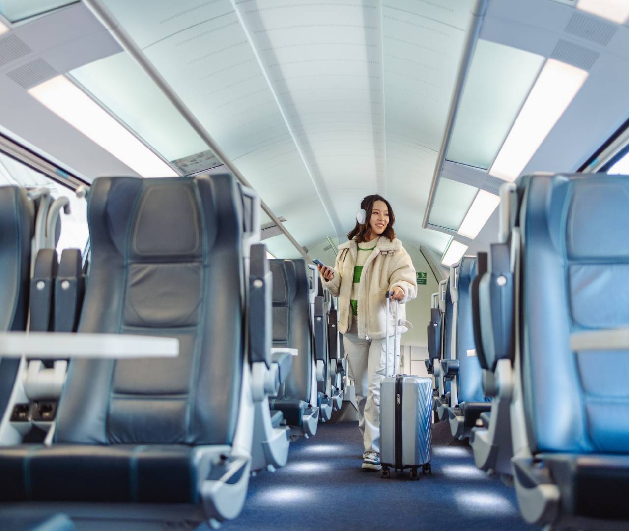 Person walking with suitcase in train aisle.
