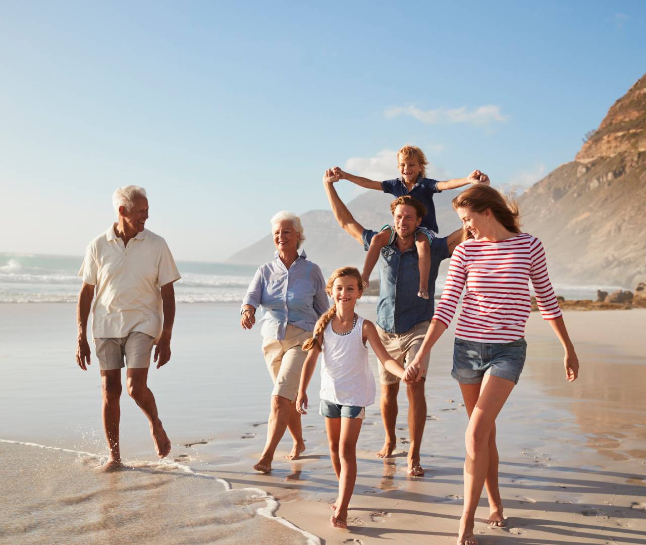 Family walking on the beach together, smiling.