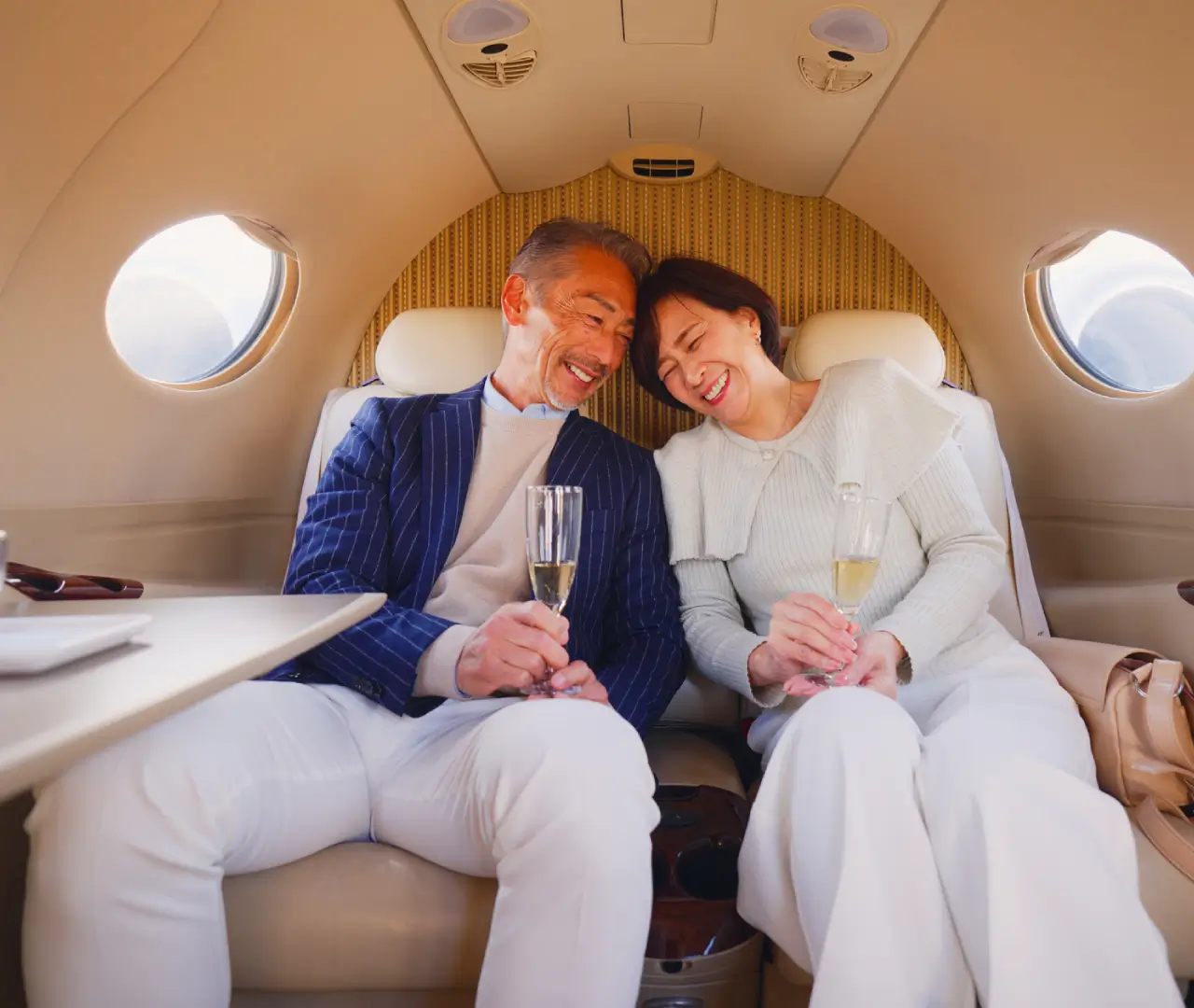Couple smiling with champagne in private jet.