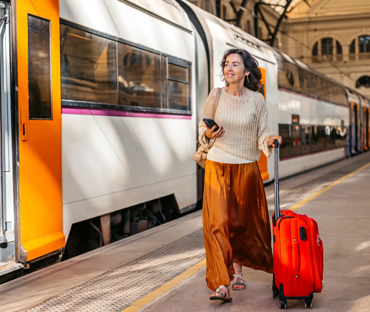 Woman with suitcase walking by train.