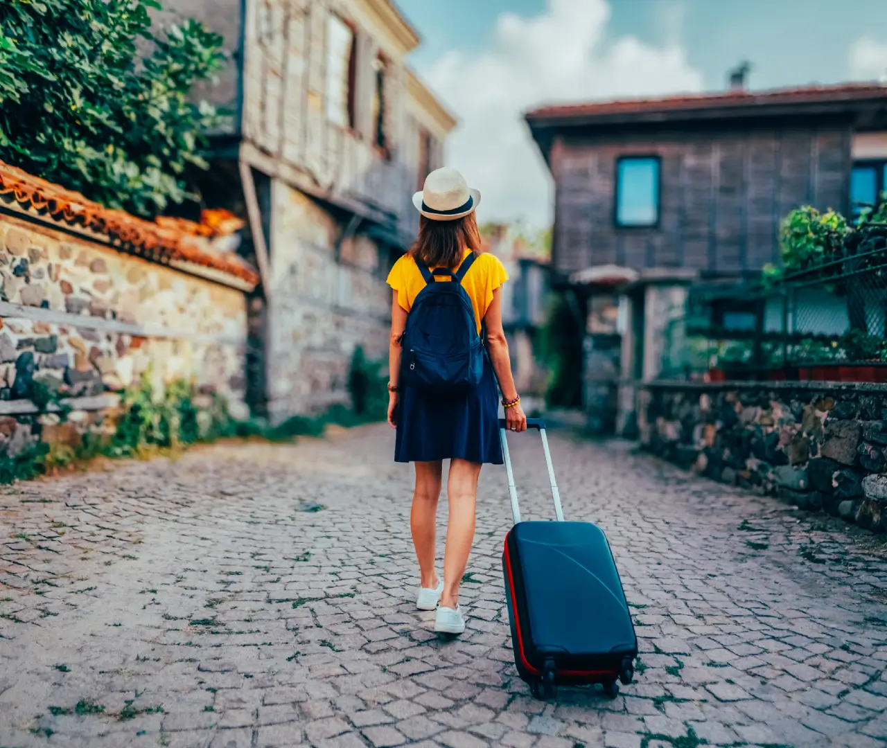 Traveler walking with suitcase on cobblestone street.