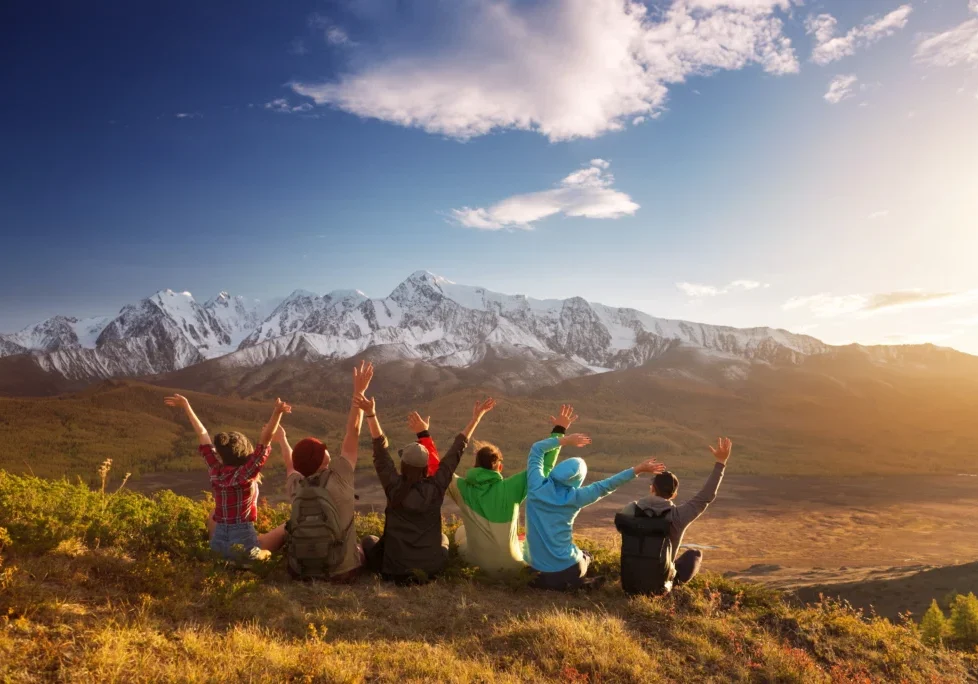 Group celebrating in front of snowy mountains.